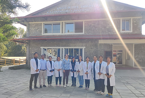 Iva Brcic und lokale Ärzt*innen und Studierende vor dem Dhulikhel Hospital Lehrkrankenhaus der Kathmandu University School of Medical Sciences    