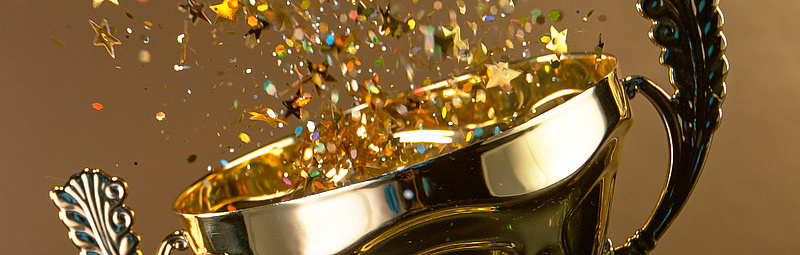 Preisverleihung Ein Pokal aus dem Confetti sprüht auf goldenem Hintergrund